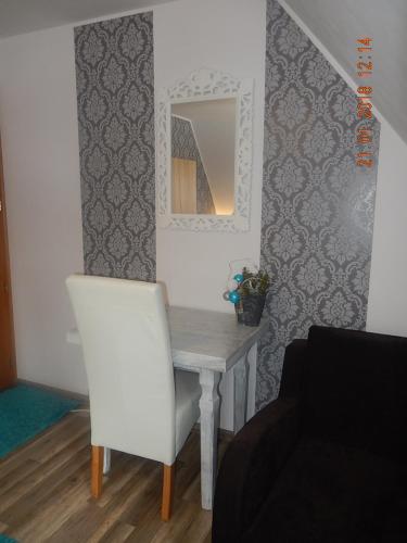 a dining room table with a white chair and a mirror at U Hanki in Biały Dunajec