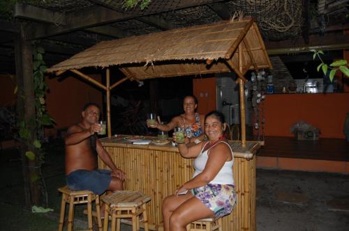 um grupo de pessoas sentadas num bar com bebidas em Pousada Alegria em Santa Cruz Cabrália