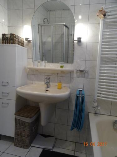 a bathroom with a sink and a mirror and a tub at Ferienwohnung Haus Nr. 11 in Warendorf