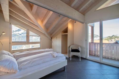 a bedroom with a bed and large windows at Chalet Brunner Penthouse in Wengen
