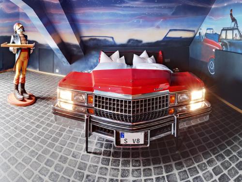 a room with a red car parked in a garage at V8 HOTEL Classic Motorworld Region Stuttgart in Böblingen