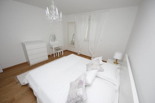 a white bedroom with a white bed and a chandelier at Villa More in Makarska