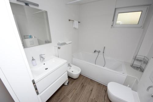 a white bathroom with a sink and a tub and a toilet at Villa More in Makarska