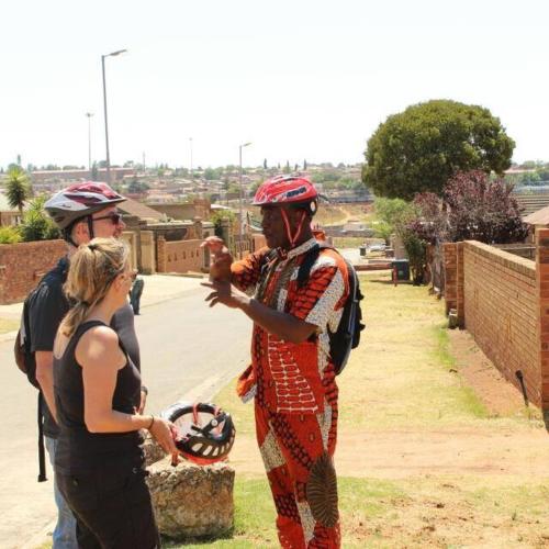 a group of people wearing helmets talking to a woman at Authentic Bicycle Tours and Backpackers in Soweto