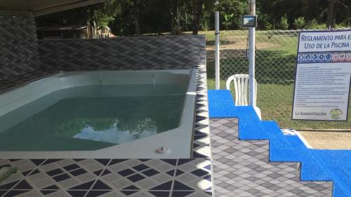 a swimming pool with a sign next to a fence at Club campestre el Peñón de Apulo in Apulo