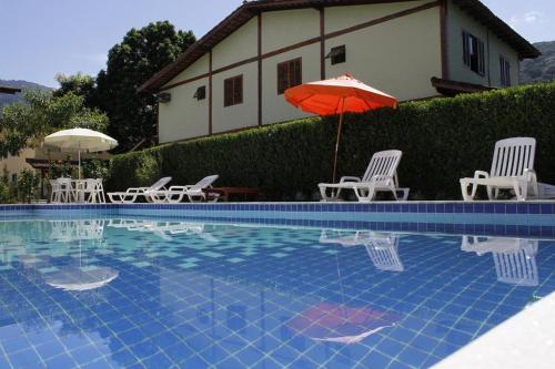 een zwembad met stoelen en een rode parasol bij casa em condomínio com piscina in Maresias