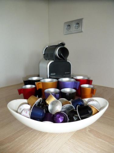 a white bowl filled with lots of different colored cups at Silver DeLux Apartman in Balatonfüred