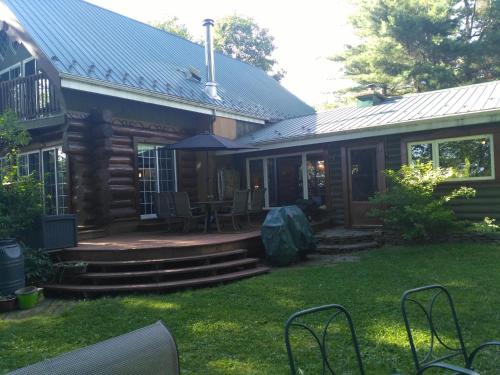a log cabin with a porch and a patio at Le petit Montebello in Grenville-sur-la-Rouge