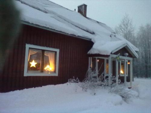 a cabin with a christmas star in a window at Christinagården Guesthouse in Ramsele