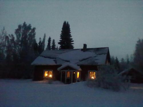 a house with lights in the snow at night at Christinagården Guesthouse in Ramsele