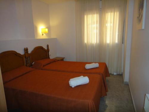 two beds in a room with red sheets and white towels at Bertur Gran Reserva Comte Empuries in Empuriabrava