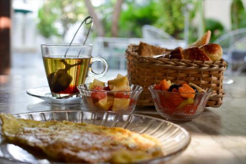 a table with a bowl of fruit and a basket of bread at Villa Helena in Puducherry