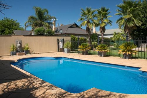 uma piscina em frente a uma cerca com palmeiras em Barossa Dreams em Tanunda