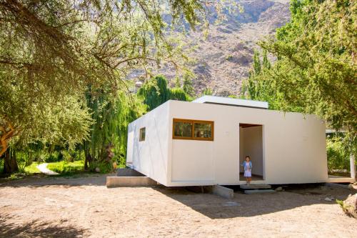 a woman standing in the doorway of a white house at Aldea del Valle - Elqui Villas, Pisco Elqui in Pisco Elqui