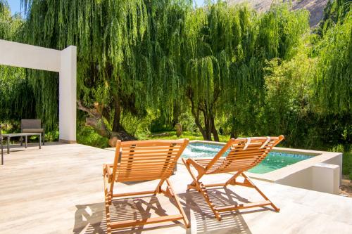 two chairs sitting on a deck next to a swimming pool at Aldea del Valle - Elqui Villas, Pisco Elqui in Pisco Elqui