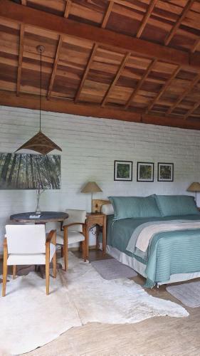 a bedroom with a bed and a table in it at Pousada Pinho Bravo in Camanducaia