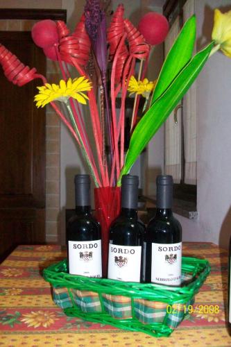 three bottles of wine sitting on a table with flowers at Tra... Monti E Vigne in La Morra