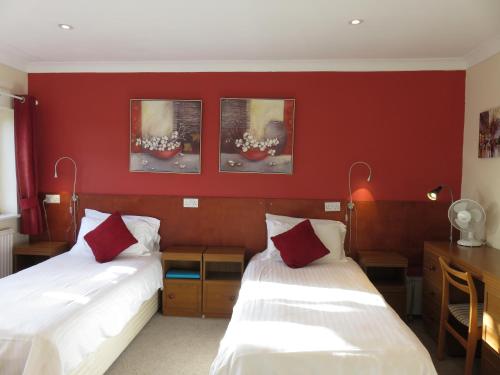 two beds in a room with red walls at Cherry Lodge in Hook