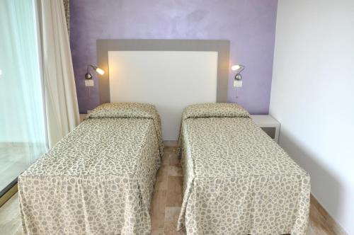 two beds in a room with purple walls at Gil's Hotel in Olbia
