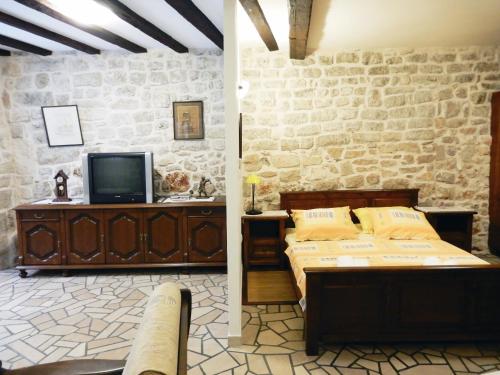 1 dormitorio con 1 cama, TV y pared de piedra en Apartment Primorac, en Stari Grad