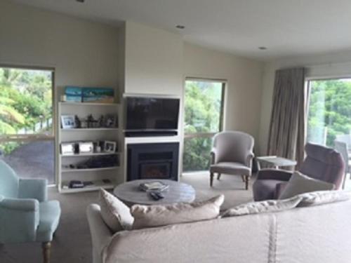 a living room with a couch and chairs and a tv at Hahei Sea Vista (2) in Hahei