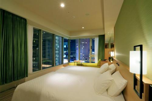 a bedroom with a large white bed with a large window at THE SINGULARI HOTEL & SKYSPA at UNIVERSAL STUDIOS JAPAN in Osaka