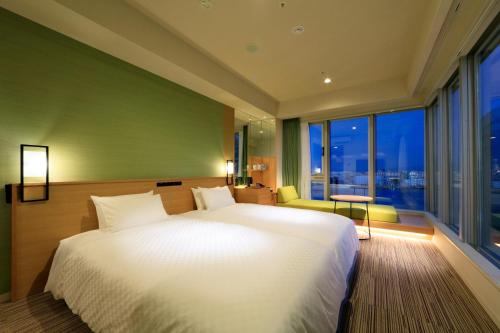 a bedroom with a white bed and a large window at THE SINGULARI HOTEL & SKYSPA at UNIVERSAL STUDIOS JAPAN in Osaka