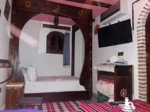 a room with a bed and a tv at Dar naya in Chefchaouene