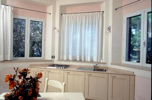 a kitchen with two windows and a sink and a table at Hotel Rossi in Manciano