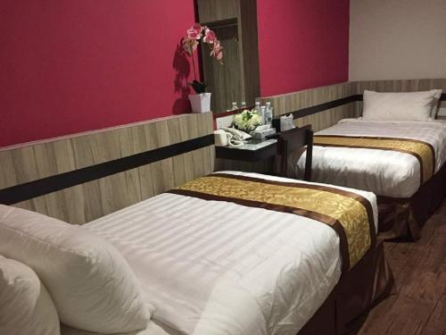 a hotel room with two beds and a pink wall at Meriton Inn in Kuantan