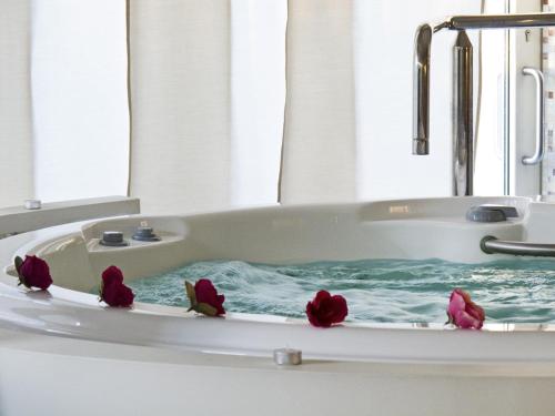 a bath tub with three red flowers in it at Palace Hotel in Milano Marittima