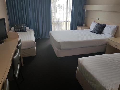 a hotel room with two beds and a television at Acacia Motel in Griffith
