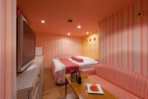 a hotel room with a bed and a couch and a television at ホテル ブランチャペルクリスマス 四日市 in Yokkaichi