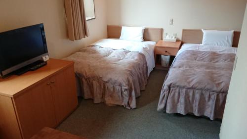 a hotel room with two beds and a flat screen tv at Hotel Muroran Hills in Muroran