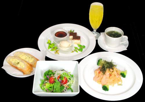 a table with plates of food and a glass of orange juice at Sakaihama Rakuten Onsen Shofuku in Sakai