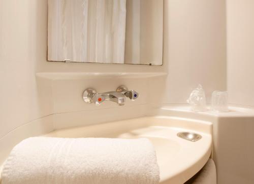 a white bathroom with a sink and a mirror at Premiere Classe Valenciennes Sud - Rouvignies in Valenciennes