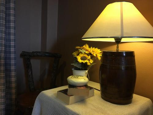 a lamp sitting on a table with a vase of flowers at The Green land (Khok Kruat) in Nakhon Ratchasima