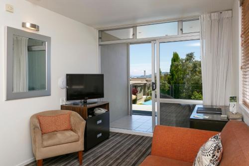 ein Wohnzimmer mit einem Sofa, einem TV und einem Fenster in der Unterkunft The Reef Resort in Taupo