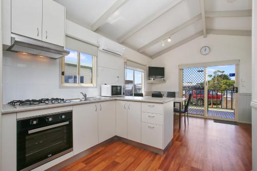 a kitchen with white cabinets and a stove top oven at BIG4 Apollo Bay Pisces Holiday Park in Apollo Bay