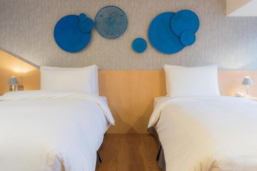 two beds in a room with blue plates on the wall at Hej Taipei in Taipei