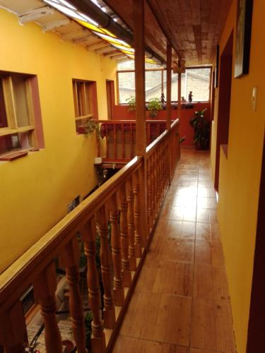 a hallway in a house with yellow walls and wooden stairs at B&B Chayana Wasi in Ollantaytambo