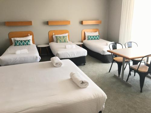 a room with three beds and a table and chairs at Cascades Motor Inn in Dubbo