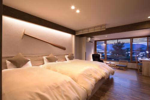 a bedroom with two beds and a desk and a window at Hotel Miyajima Villa in Miyajima
