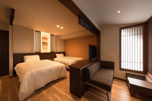 a hotel room with two beds and a chair at Hotel Miyajima Villa in Miyajima