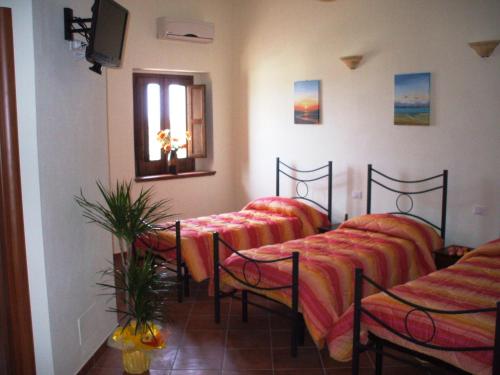 een kamer met 4 bedden, een raam en een tv bij Affittacamere Il Borgo in Francavilla Marittima