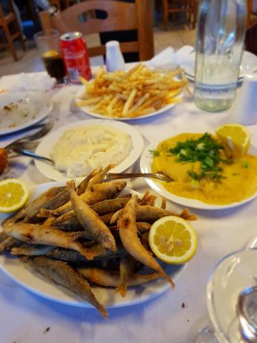 a table with plates of food with fish and french fries at Sounio Palea Heaven in Palaiá Fókaia