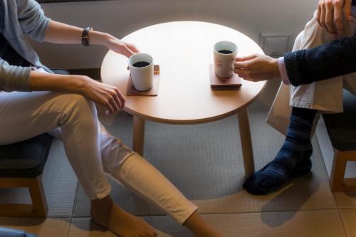 a group of people sitting around a table with coffee cups at Hotel Miyajima Villa in Miyajima