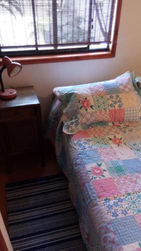 a bedroom with a bed and a table and a window at Cabaña 1 Neuling-Reñaca in Viña del Mar