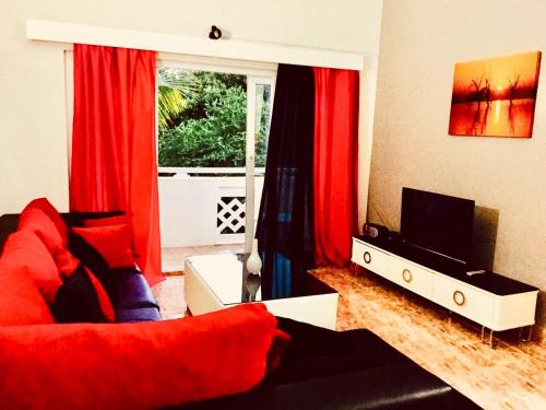 a living room with a red couch and a television at Sonnige Ferienwohnung mit Wifi in Flic-en-Flac