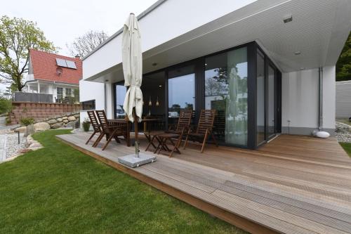 una terraza de madera con sillas y una sombrilla en una casa en Haus Windsbraut - FeWo 01, en Ostseebad Sellin